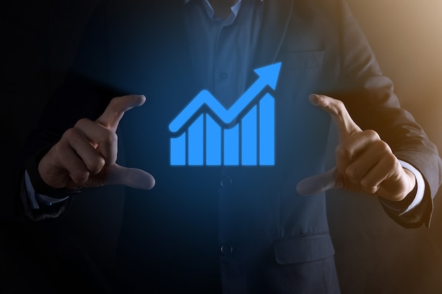 Businessman holding a graph with positive profits growth