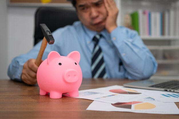 Businessman holding hammer And is breaking the piggy bank