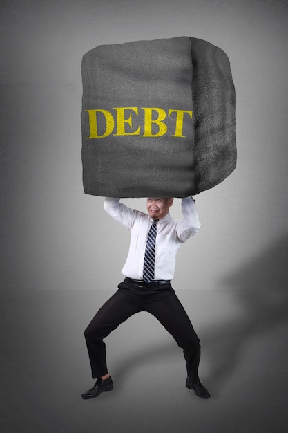 Photo businessman holding heavy stone of debt over his head