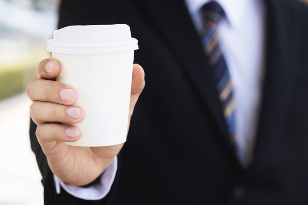 Un uomo d'affari che tiene una tazza di caffè calda, ha bevuto il caffè prima del lavoro la mattina