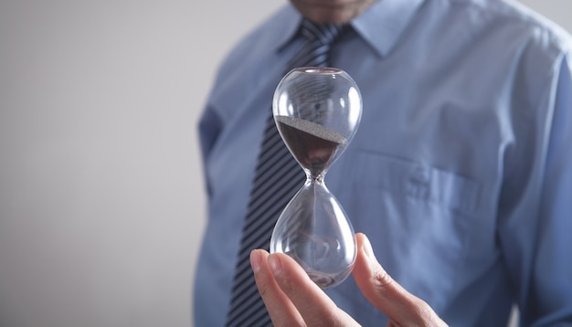 Businessman holding hourglass. Deadline concept