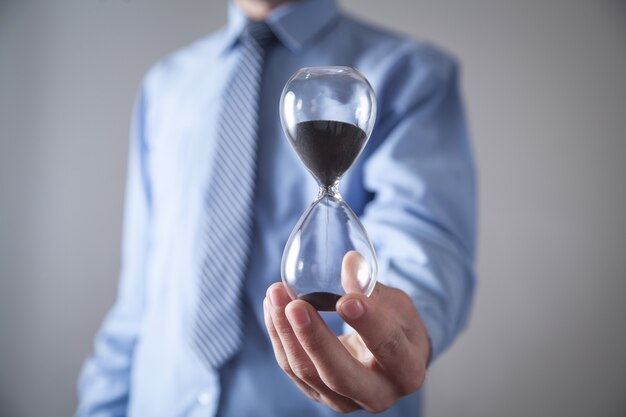 Businessman holding hourglass. Deadline concept