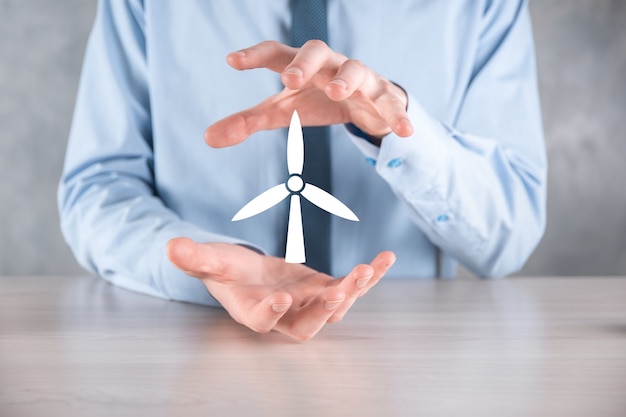 Businessman holding an icon of a windmill that produces environmental energy