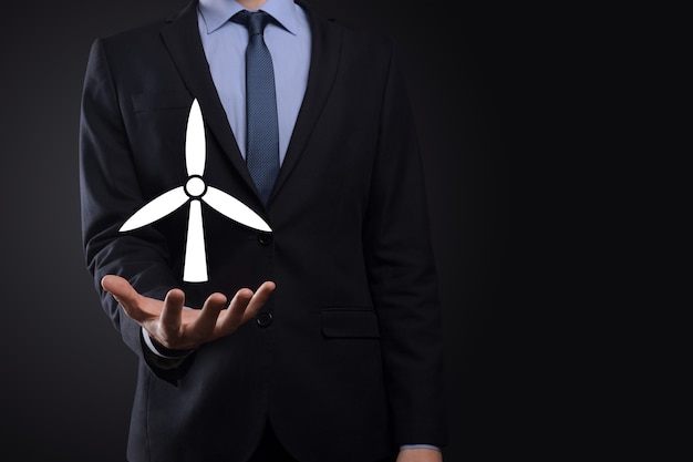 Businessman holding an icon of a windmill that produces environmental energy