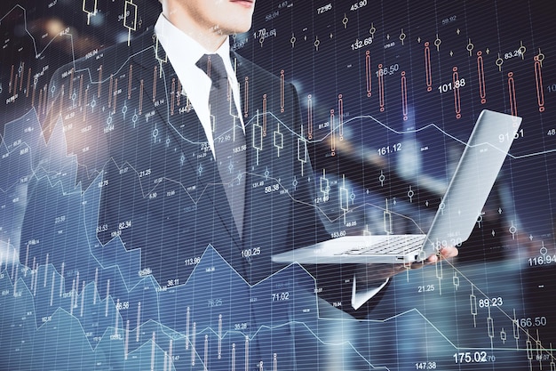 Бизнесмен держит ноутбук с голограммой падающей статистики акций