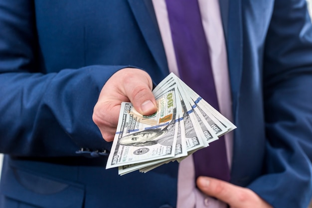 Businessman holding large amount of dollar and give you