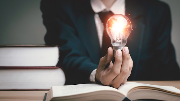 Businessman holding a light bulb think problem solving business competition planning teamworkInternational book ideas and competition and strategy business success conceptstrategic concept