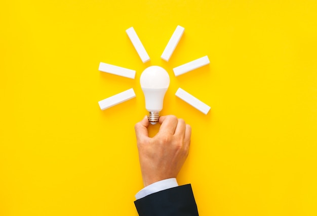 Businessman holding light bulb with wooden blocks with copy space. Business start-up goals