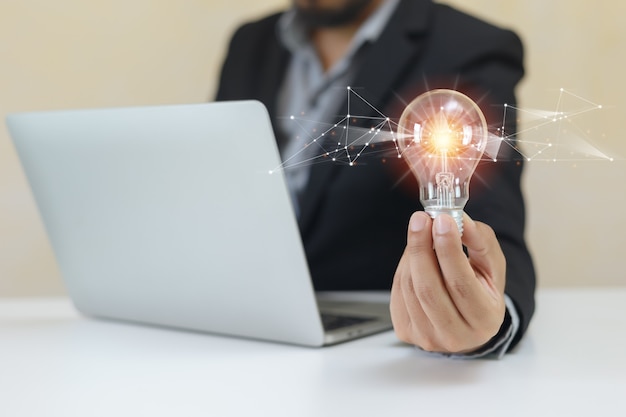 Businessman holding light bulbs using laptop. think creative innovation. power vision and ideas concept.