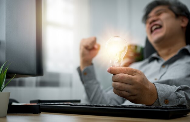 Businessman holding lightbulb and feeling delighted and excited by new ideas