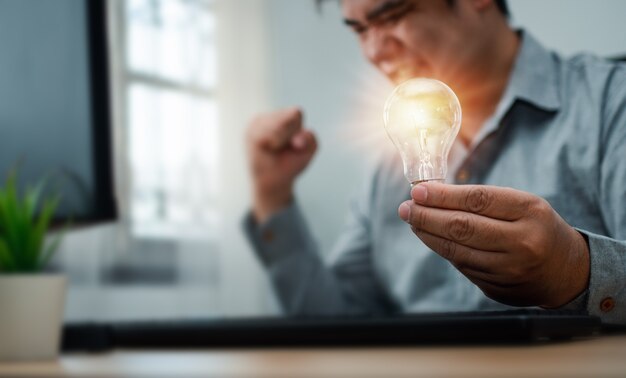 Businessman holding lightbulb and feeling delighted and excited by new innovation and ideas for success business panels.