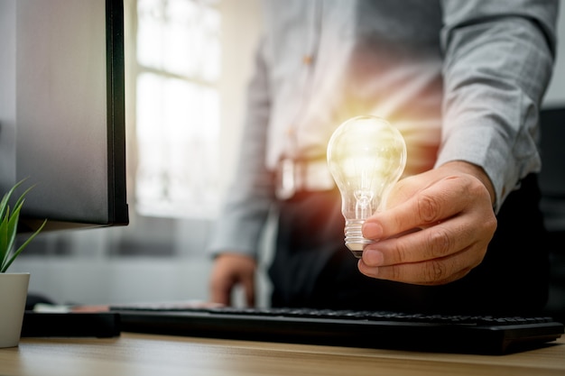 Businessman holding lightbulb and feeling happy by new innovation and ideas