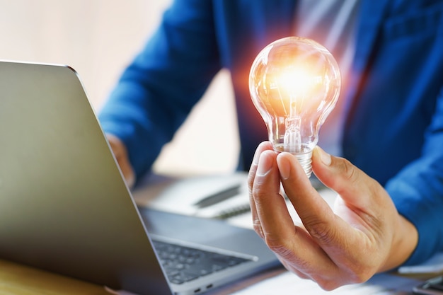 businessman holding lightbulb in office