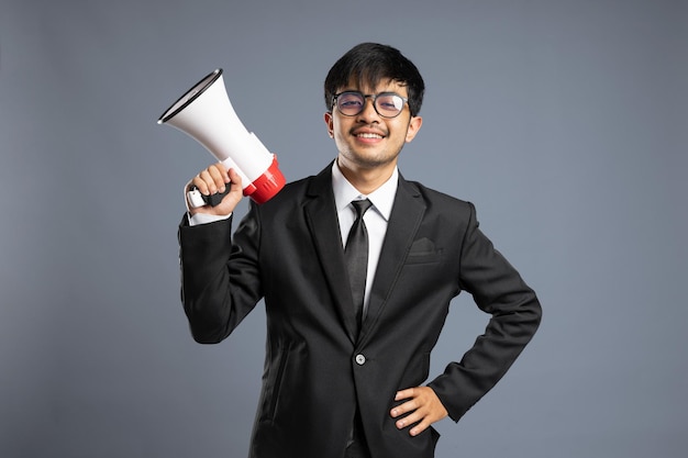 Businessman holding megaphone isolated on grey background