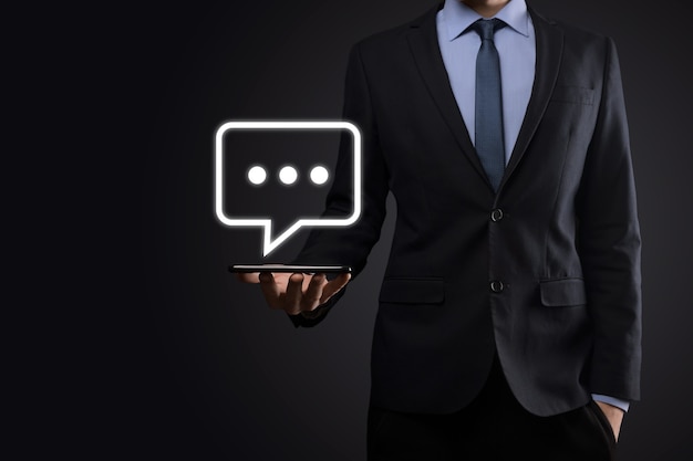 Businessman holding a message icon, bubble talk notification sign in his hands. Chat icon, sms icon, comments icon, speech bubbles