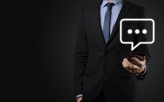 Businessman holding a message icon, bubble talk notification sign in his hands. Chat icon, sms icon, comments icon, speech bubbles.