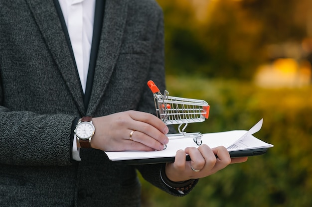 Businessman holding a miniature shopping cart