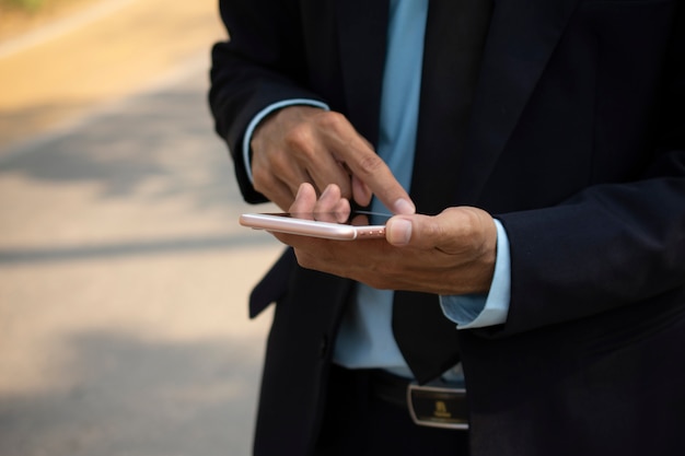 Businessman holding mobile smart phone and using smart phone for business connection