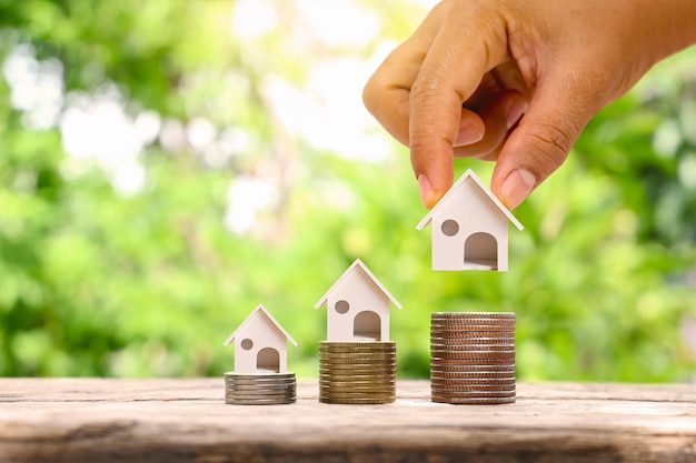 businessman holding model house and model house on a pile of coins real estate investment concept Mortgage and home building interest rates