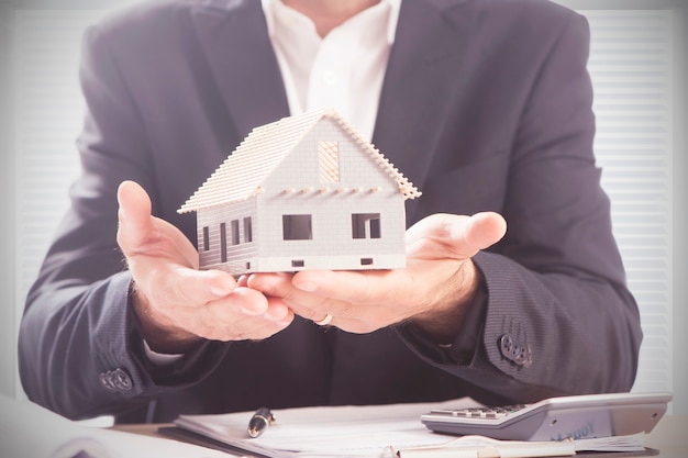 businessman holding model house in palm of hand