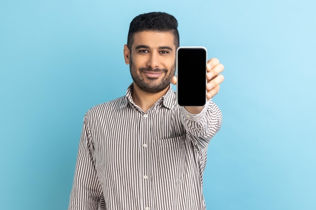 Businessman holding out cellphone and smiling at camera recommending gadget or mobile application