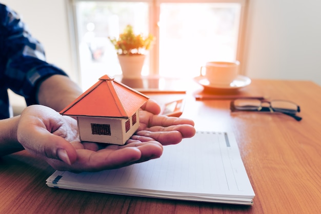 Businessman holding paper home model. Loan concept