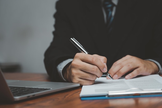 Businessman holding pen signature document on clipboard at desk Business information insurance lawyer and job concept