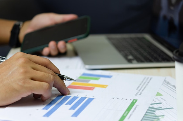 Businessman holding pen to work computer graphs and charts data statistical data financial analysis documents