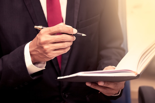 Businessman holding a pen to write on notebook