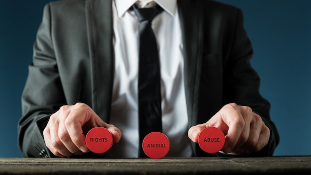 Businessman holding red wooden cut circles with animal right and animal abuse sign in a conceptual image