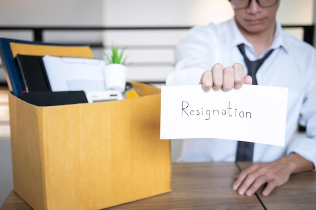 Businessman holding resignation letter at table in office
