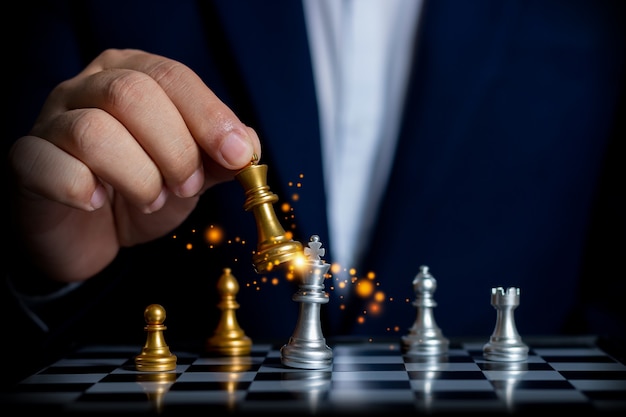 Businessman holding a shining golden chess to use competitors business strategy for future victory