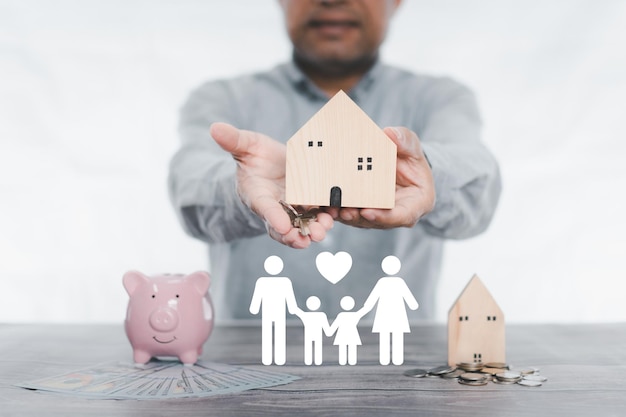 Photo businessman holding simulated wooden house and a key icon family on table donation saving charity family finance plan concept fundraising superannuation investment financial crisis concept