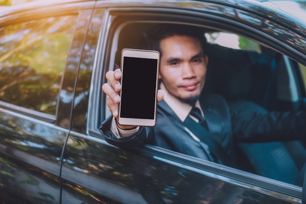 Businessman holding smart phone and sitting in car