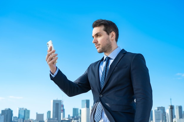 A businessman holding a smartphone and blue sky