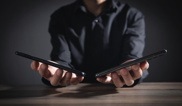 Businessman holding smartphones in office.