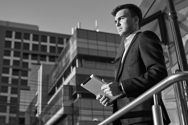 Businessman holding a tablet in hands on the background of buildings with glass facades