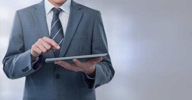 Businessman holding tablet with grey lights background