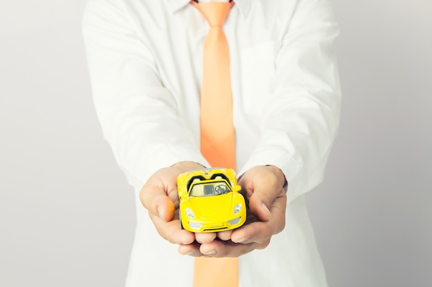 Businessman holding a toy car, isolated background