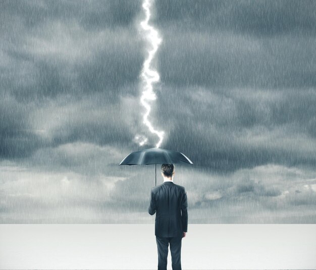 Businessman holding umbrella in storm