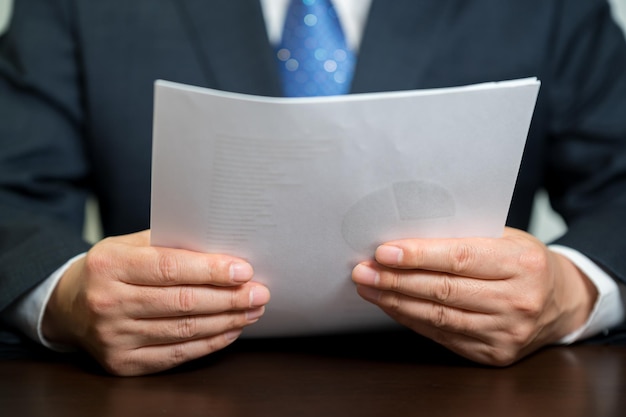 A businessman holding a white paper document.