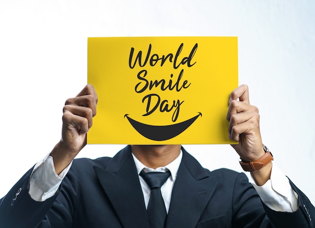 Foto uomo d'affari che tiene un manifesto giallo di giornata mondiale del sorriso