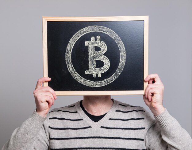 Businessman holding writing slate with bitcoin sign against white background