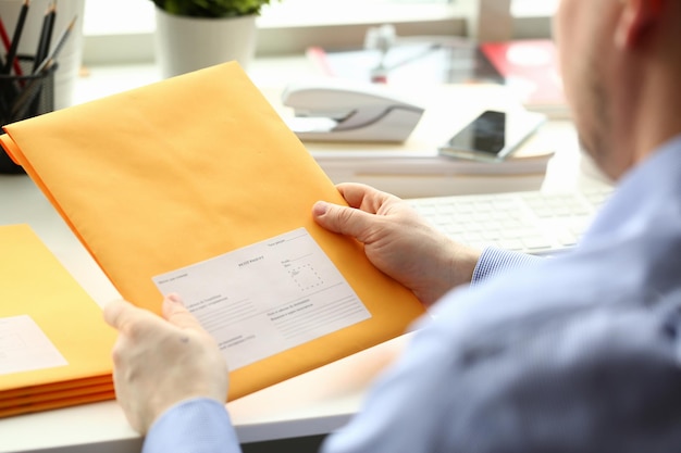 Бизнесмен держит желтый пакет с почтой в офисе