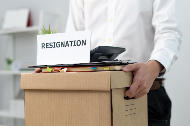 A businessman holds a box for personal items after sending a resignation letter to an executive or manager Include information about resignation and vacancies and job changes