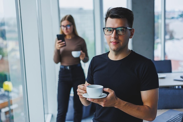 사업가는 손에 커피 한 잔을 들고 있습니다. 멀티태스킹 개념 안경 차를 마시고 카페 스마트 캐주얼에서 말하는 바쁜 프리랜서