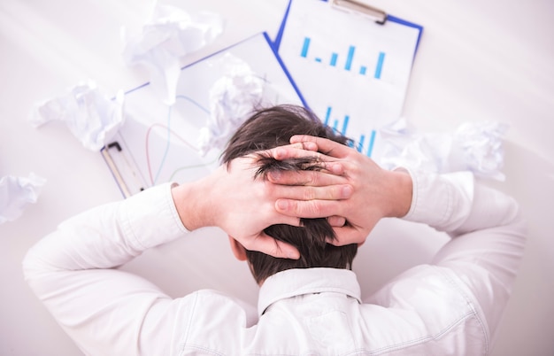 Businessman holds hands on his head and looks at documents.