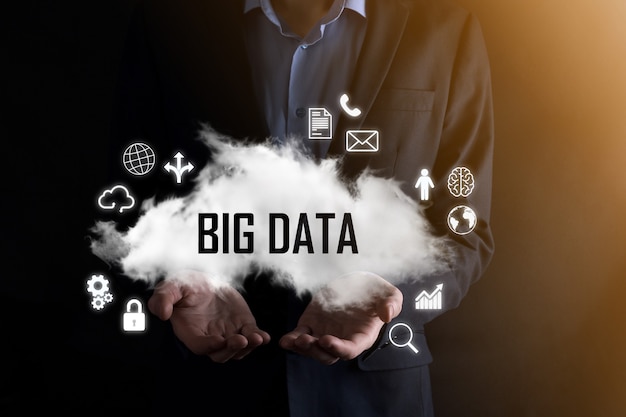 Businessman holds the inscription word big data. padlock ,\
brain ,man, planet,graph, magnifier, gears, cloud, grid, document,\
letter, phone icon.