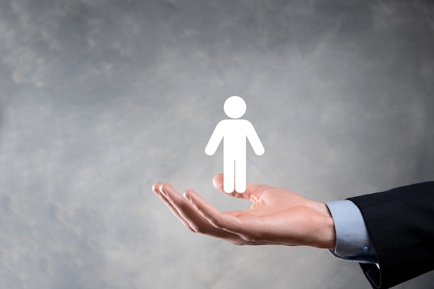 Businessman holds man person icon on dark tone wall.