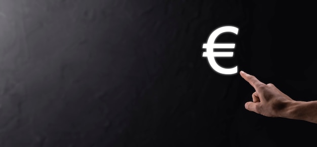 ビジネスマンは暗いトーンの背景にお金のコインアイコンEURまたはユーロを保持しています..ビジネス投資と金融のためのお金の概念を成長させる